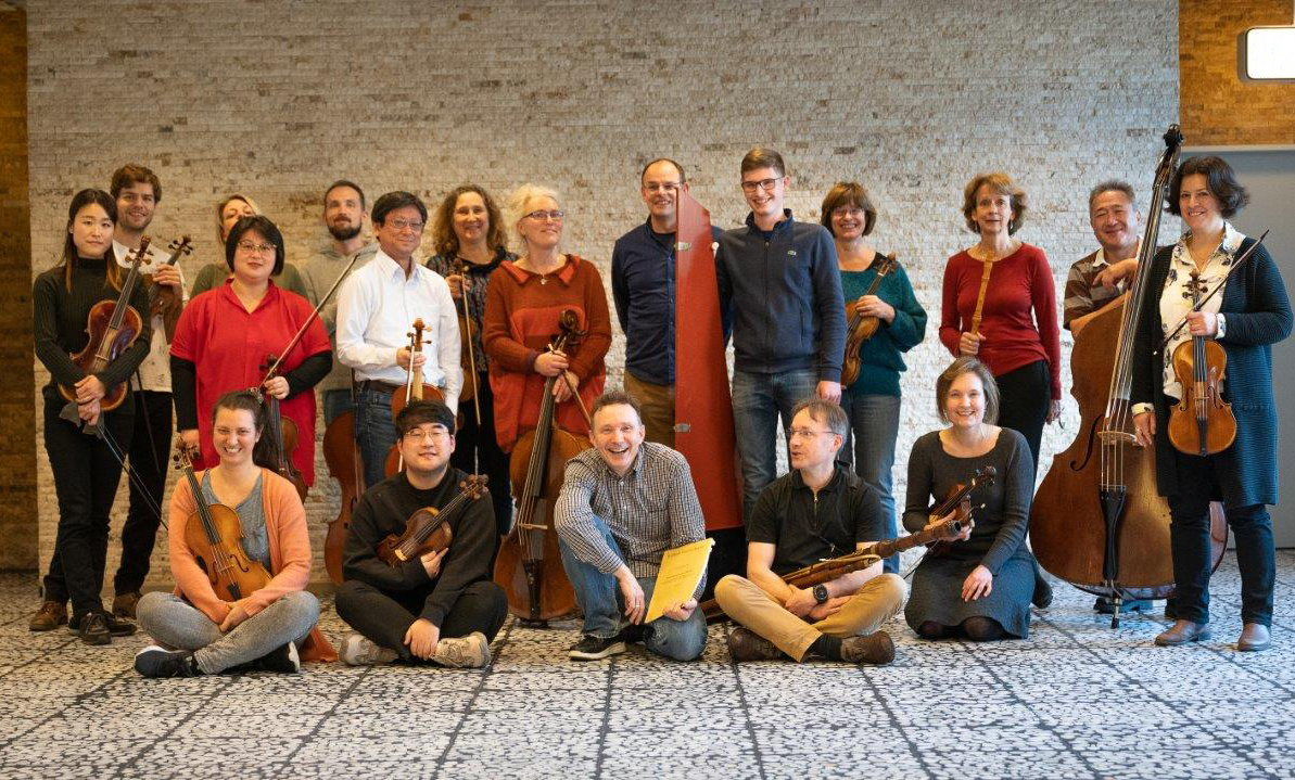 Eine Gruppe lachender Menschen mit Instrumenten.